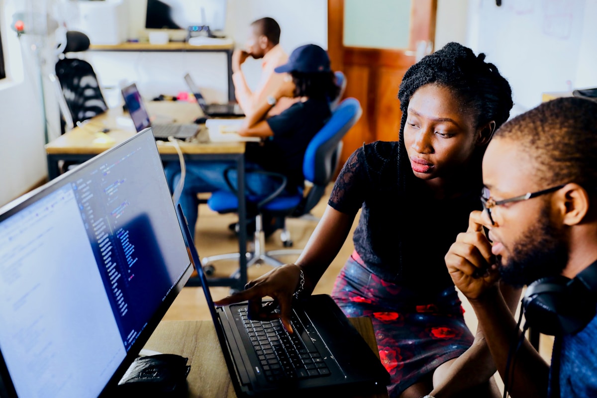 Women colleagues in discussion at a laptop in a modern city office.