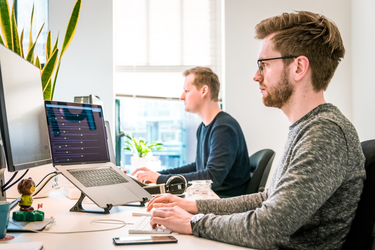 Diverse team reviewing work together at laptops in an open-plan office.
